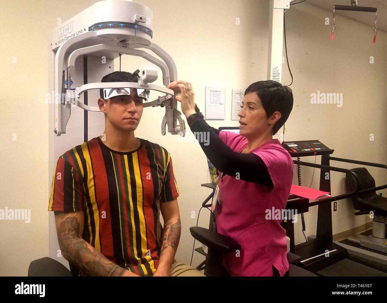 Elizabeth Fuentes, fisioterapista assistente, WBAMC, regola la testa per un paziente sull'unità Multi-Cervical per affrontare il rafforzamento dei muscoli del collo. Foto Stock