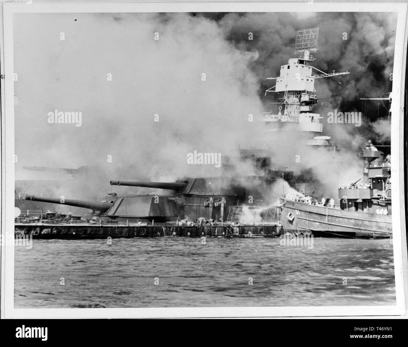 USS Tern (EM-31) per la lotta contro gli incendi a bordo della USS affondata West Virginia (BB-48), 7 dicembre, 1941, immediatamente dopo il raid giapponese. Nota antenna radar, paravanes e 16/45 twin torrette mitragliatrici sulla corazzata. (Gazzetta Foto Stock