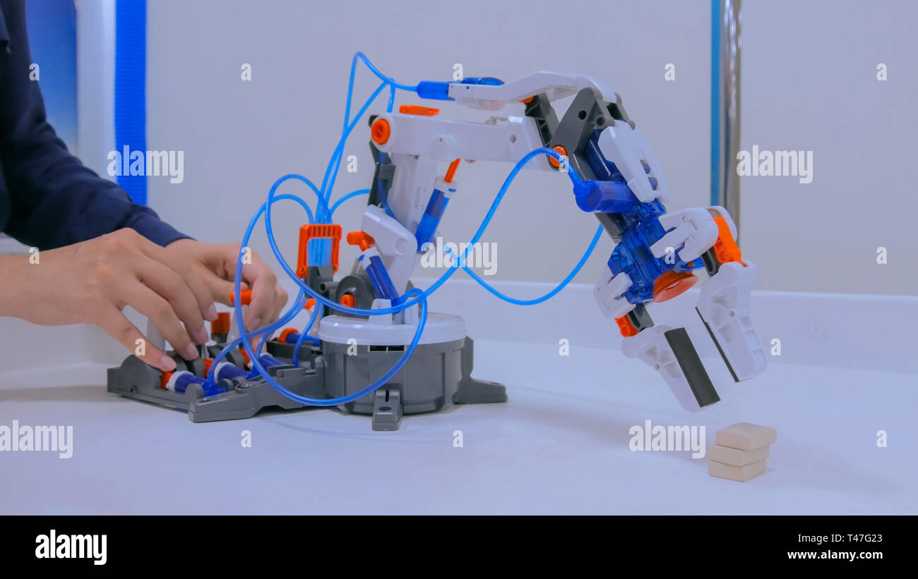 La donna controlla il robot manipolatore a mano a esposizione di tecnologia Foto Stock
