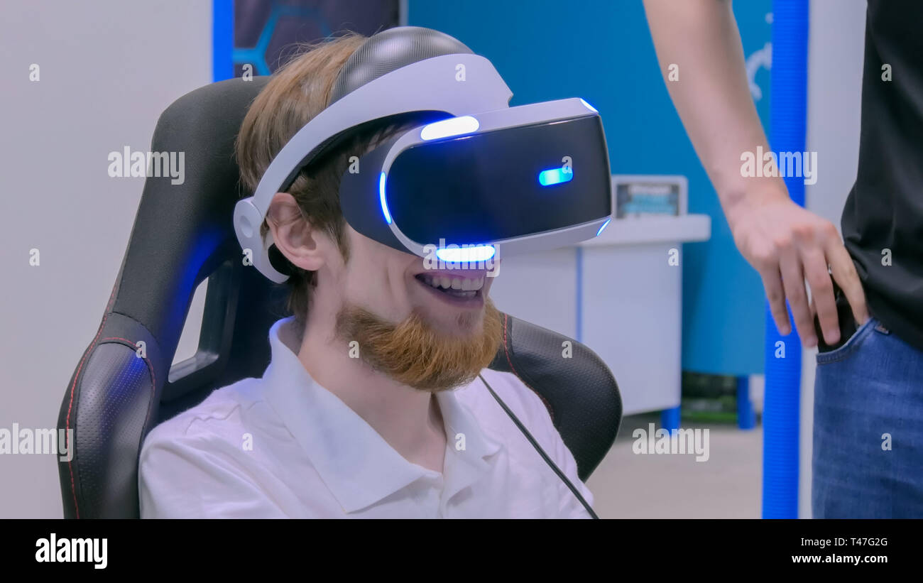 Giovane uomo sorridente e utilizzando la realtà virtuale auricolare Foto Stock