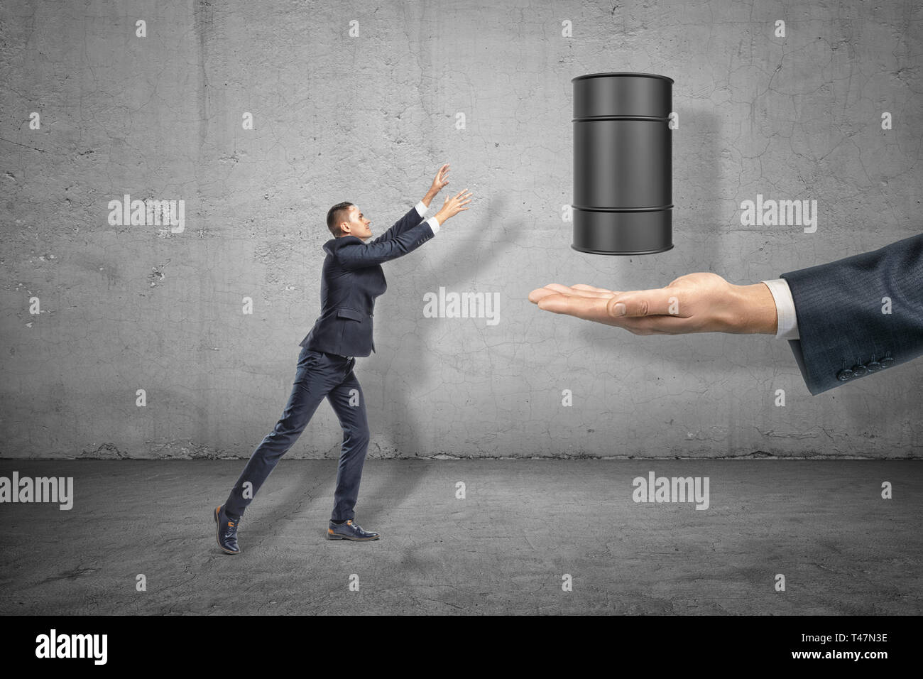 Imprenditore raggiungendo un nero cilindretto metallico su una grossa mano su sfondo grigio Foto Stock