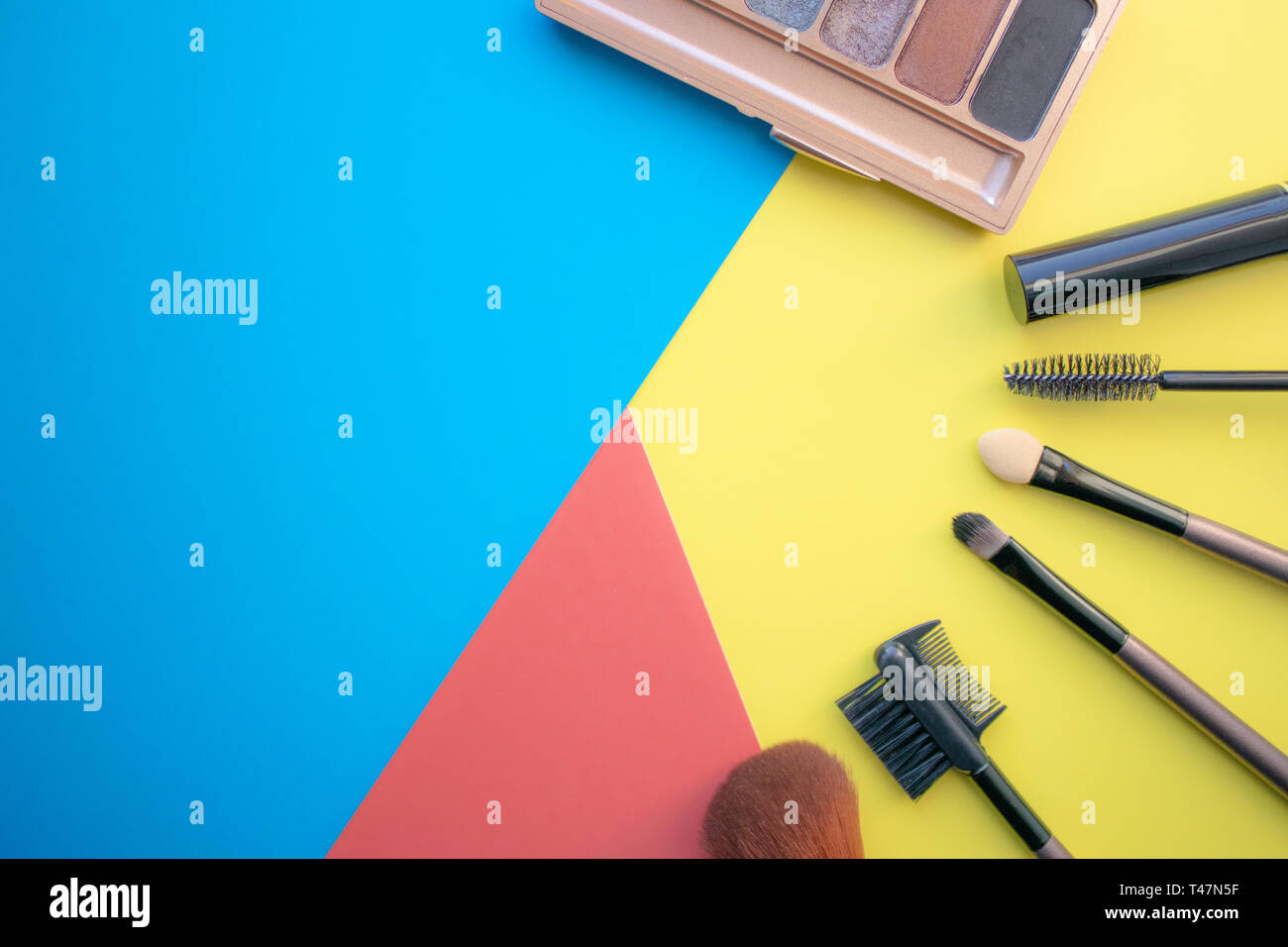 Trucco e pennelli per il trucco, occhio ombre su uno sfondo colorato. Cosmetici per il viso. Con lo spazio vuoto sulla sinistra. Vista da sopra Foto Stock