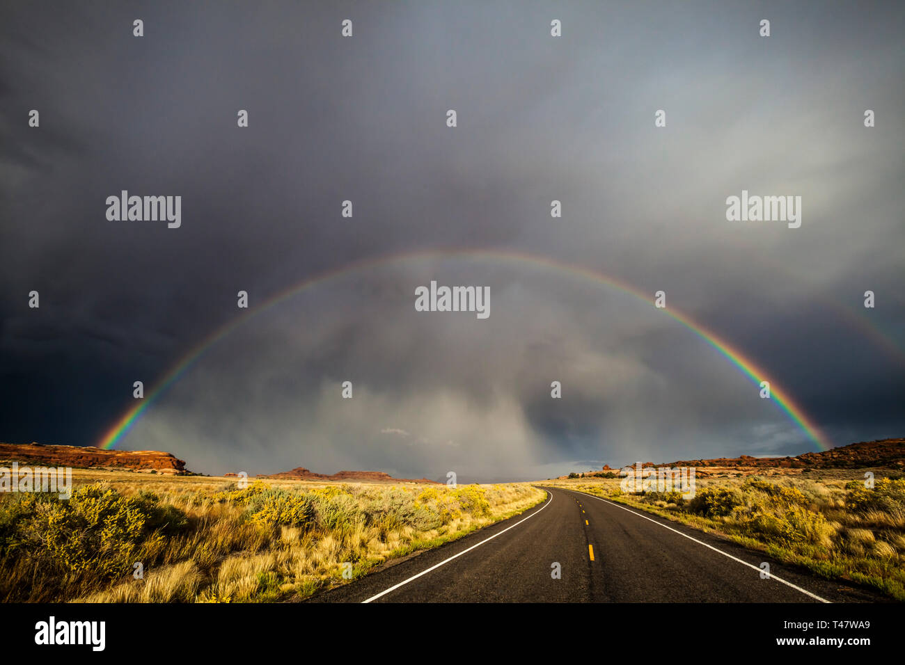 Un arcobaleno pieno e thuderstorm nubi su Scenic Highway 211 nel Parco Nazionale di Canyonlands, sudest dello Utah, Stati Uniti d'America. Foto Stock