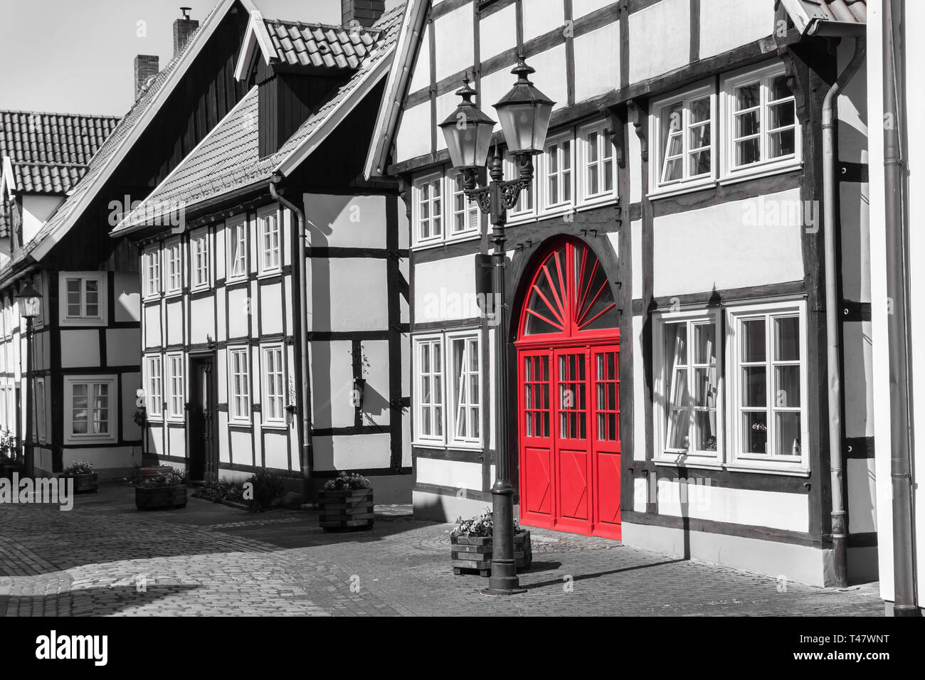 Street con metà vecchie case con travi di legno in Rheda, Germania, in bianco e nero con sportello in rosso Foto Stock