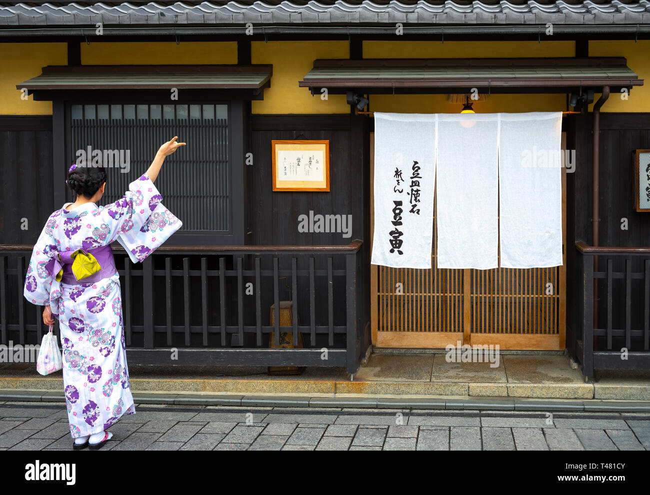 Kyoto, Giappone - 9 Giugno 2017: una ragazza locale in antico abbigliamento in posa di fronte all'entrata di un tradizionale ristorante nel quartiere di Gion Foto Stock Kyoto, Giappone - 9 Giugno 2017: una ragazza locale in antico abbigliamento in posa di fronte all'entrata di un tradizionale ristorante nel quartiere di Gion Foto Stock
