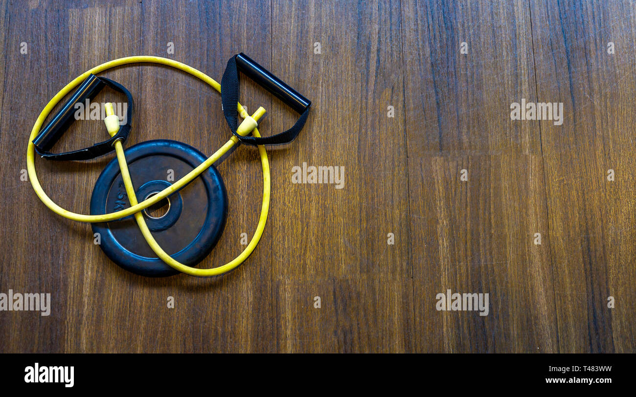 Metallo nero dal disco di manubri di sport e di un nastro elastico sul pavimento della sala fitness Foto Stock