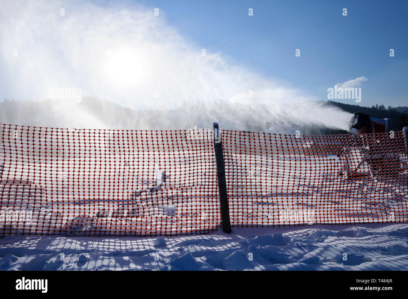 Paesaggio di montagna, stazione sciistica piste come sfondo per recinzione e innevamento artificiale con polvere bianca in aria - neve artificiale. Vacanze Inverno Foto Stock