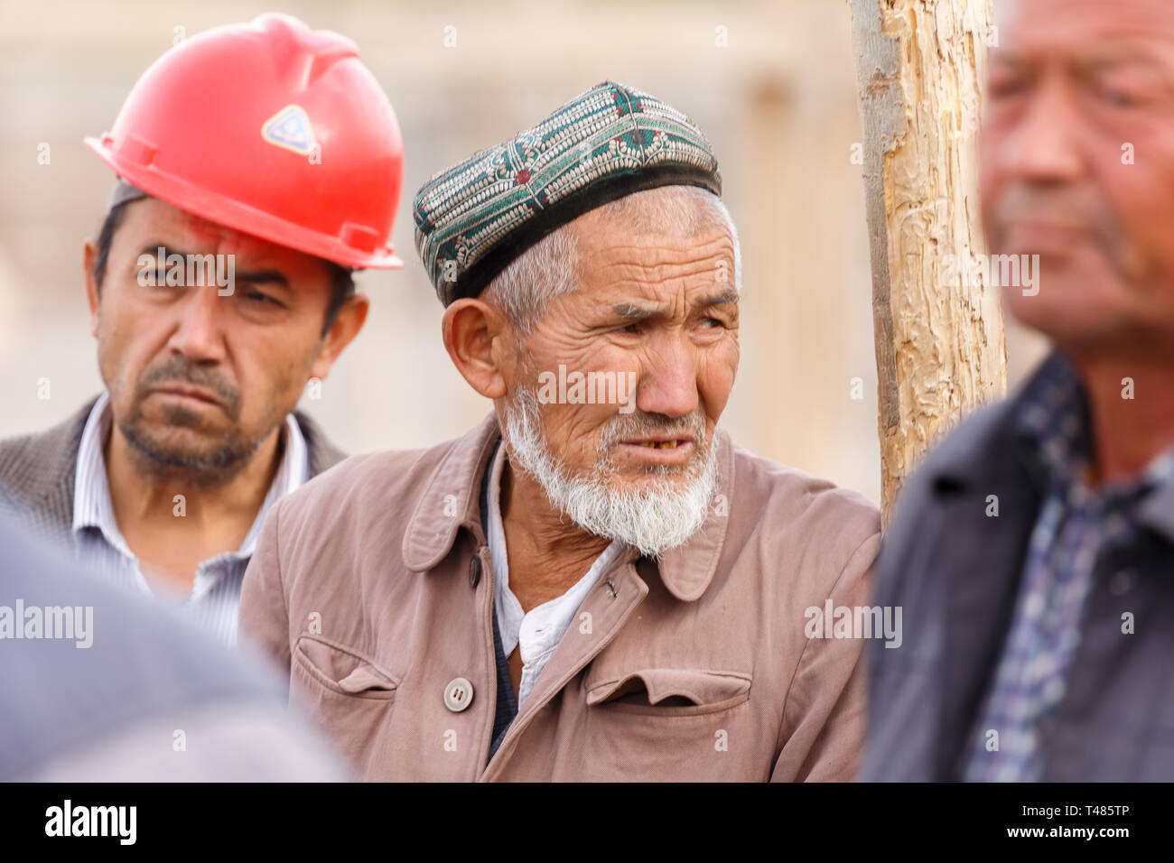 Ritratto di un anziano uomo uigura indossando un doppa (tradizionale hat). Catturato a Kashgar mercato animale (provincia dello Xinjiang Cina). Foto Stock