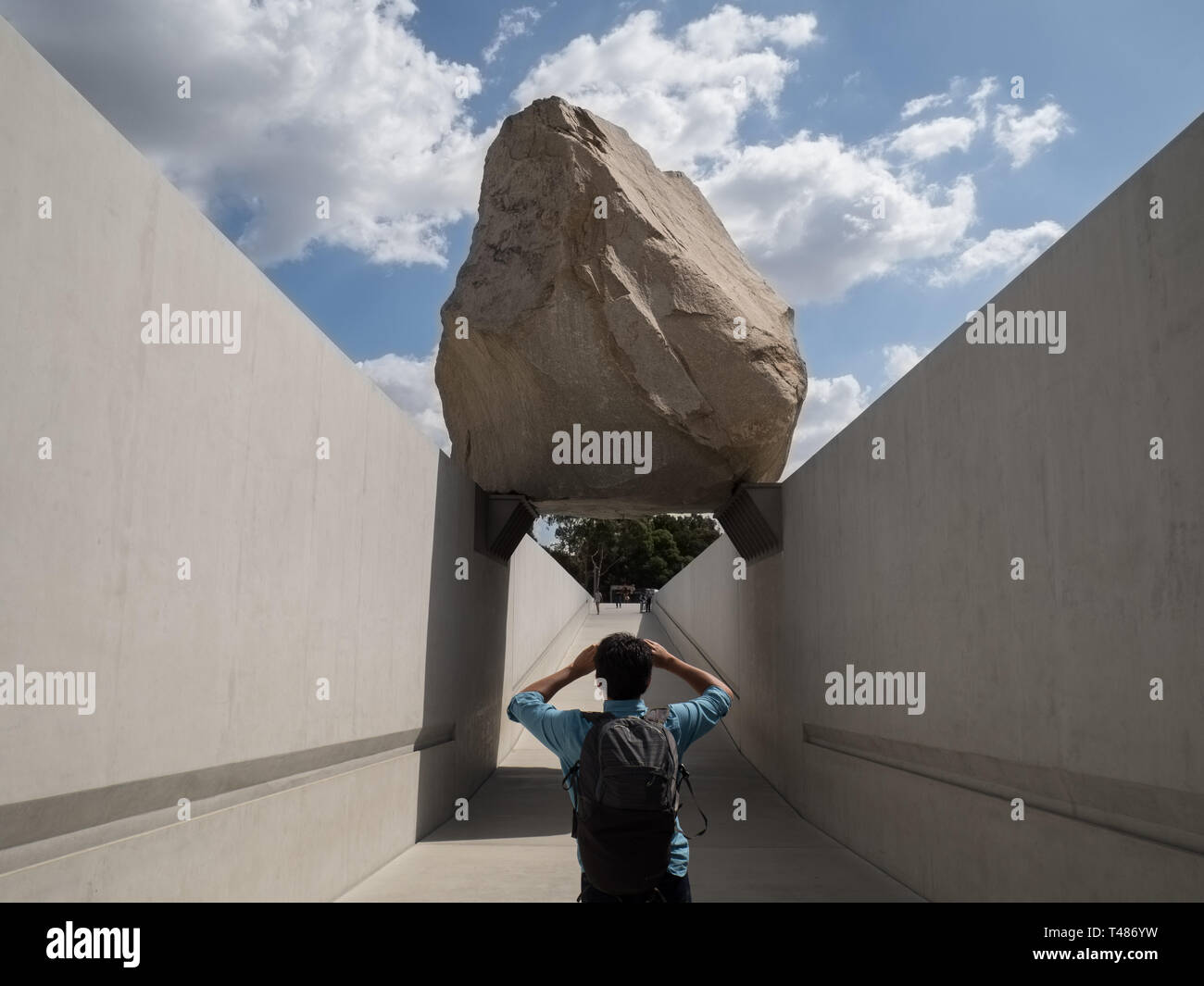 Un uomo prende una foto della massa Levitato scultura da Michael Heizer presso il Los Angeles County Museum of Art Foto Stock