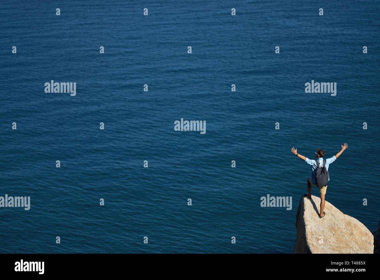 Traveler in posa sulla pietra sul litorale roccioso all'aperto Foto Stock