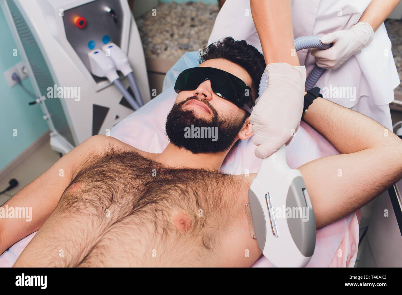 Gli uomini che giace a estetista durante il laser ascelle Depilazione terapia. Foto Stock