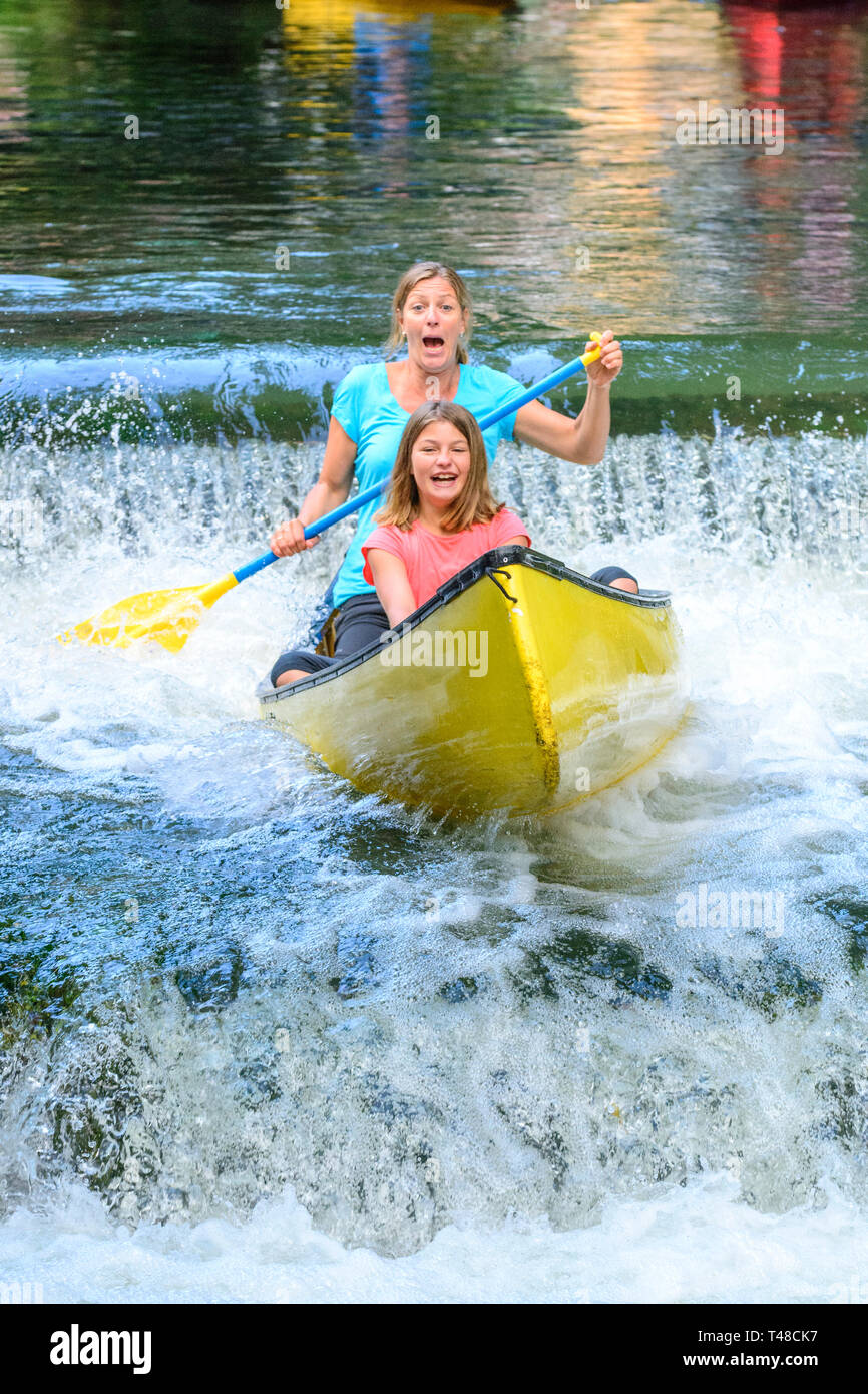 Donne paddling in basso uno stramazzo in canoa Foto Stock