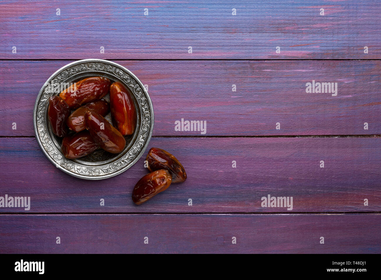 Piastra di date in viola scuro dello sfondo di legno. Lay piatto. Foto Stock