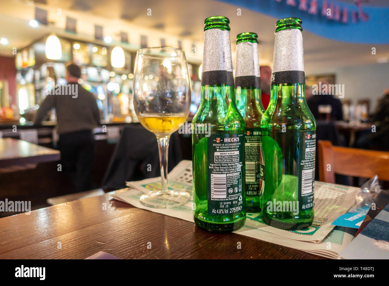 Vetro delle bottiglie di birra e un bicchiere di vino a sinistra su un tavolo in un pub. Foto Stock