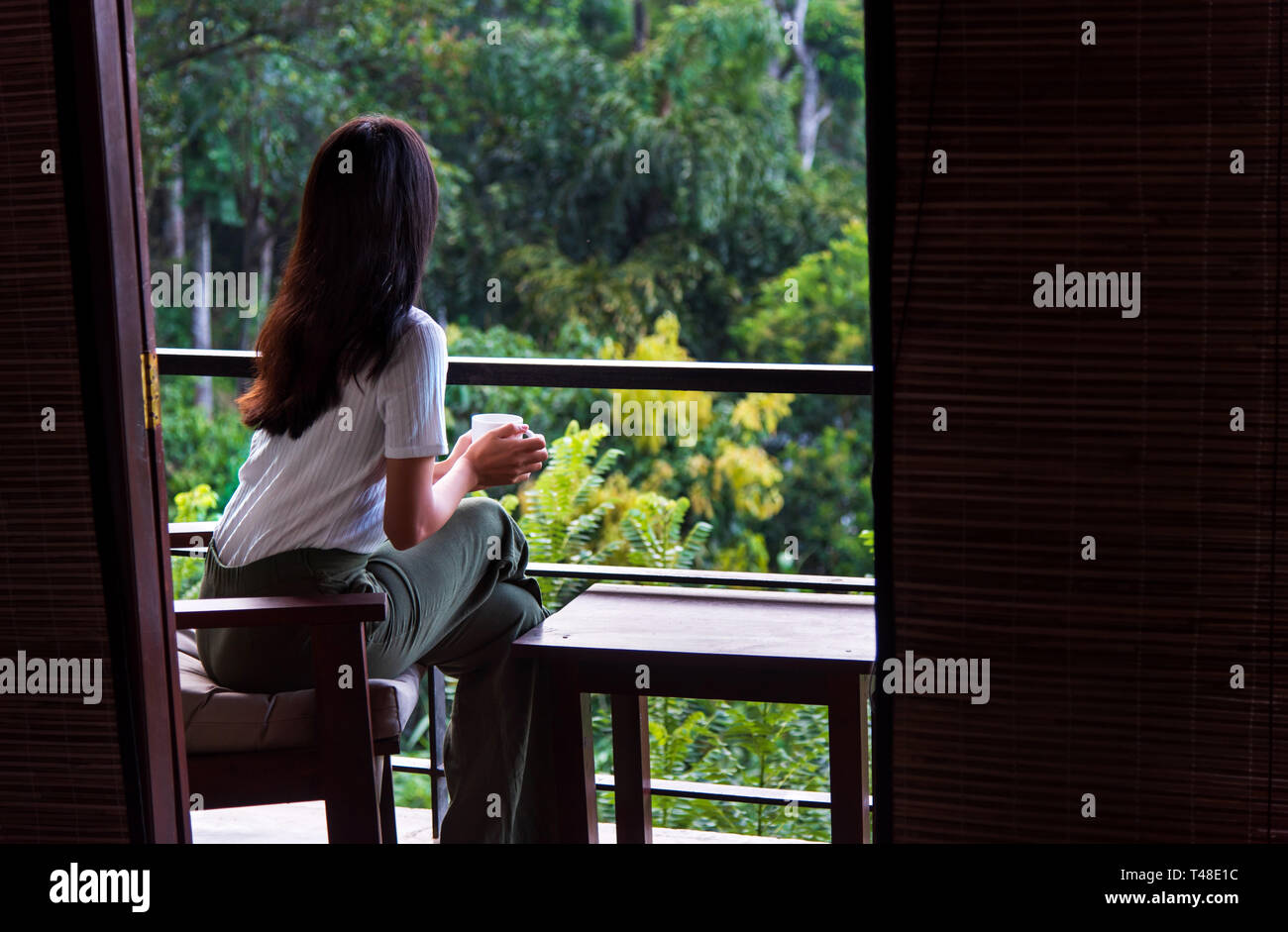 Donna con una tazza di tè sul balcone da solo Foto Stock