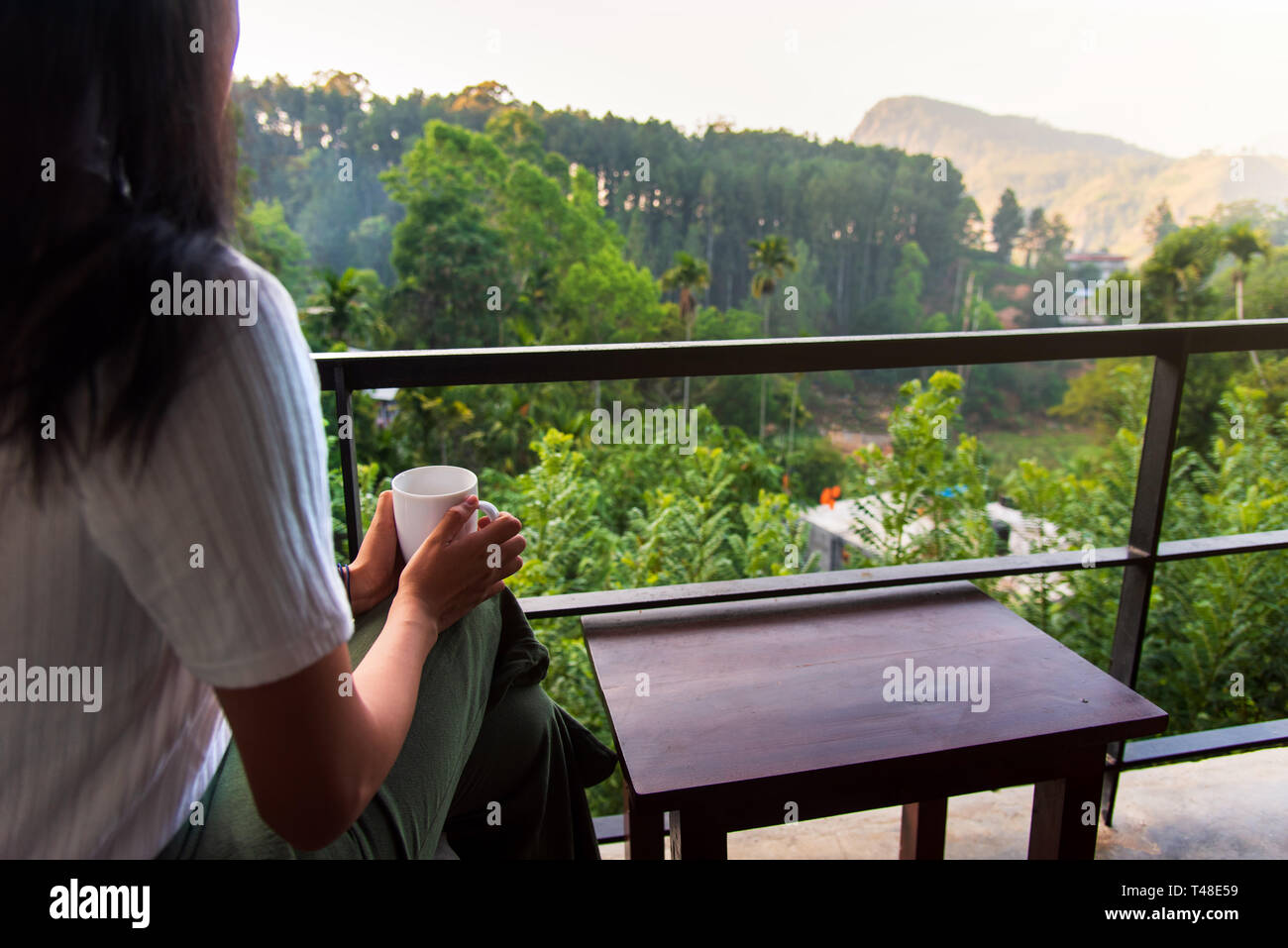 Donna con una tazza di tè sul balcone da solo Foto Stock