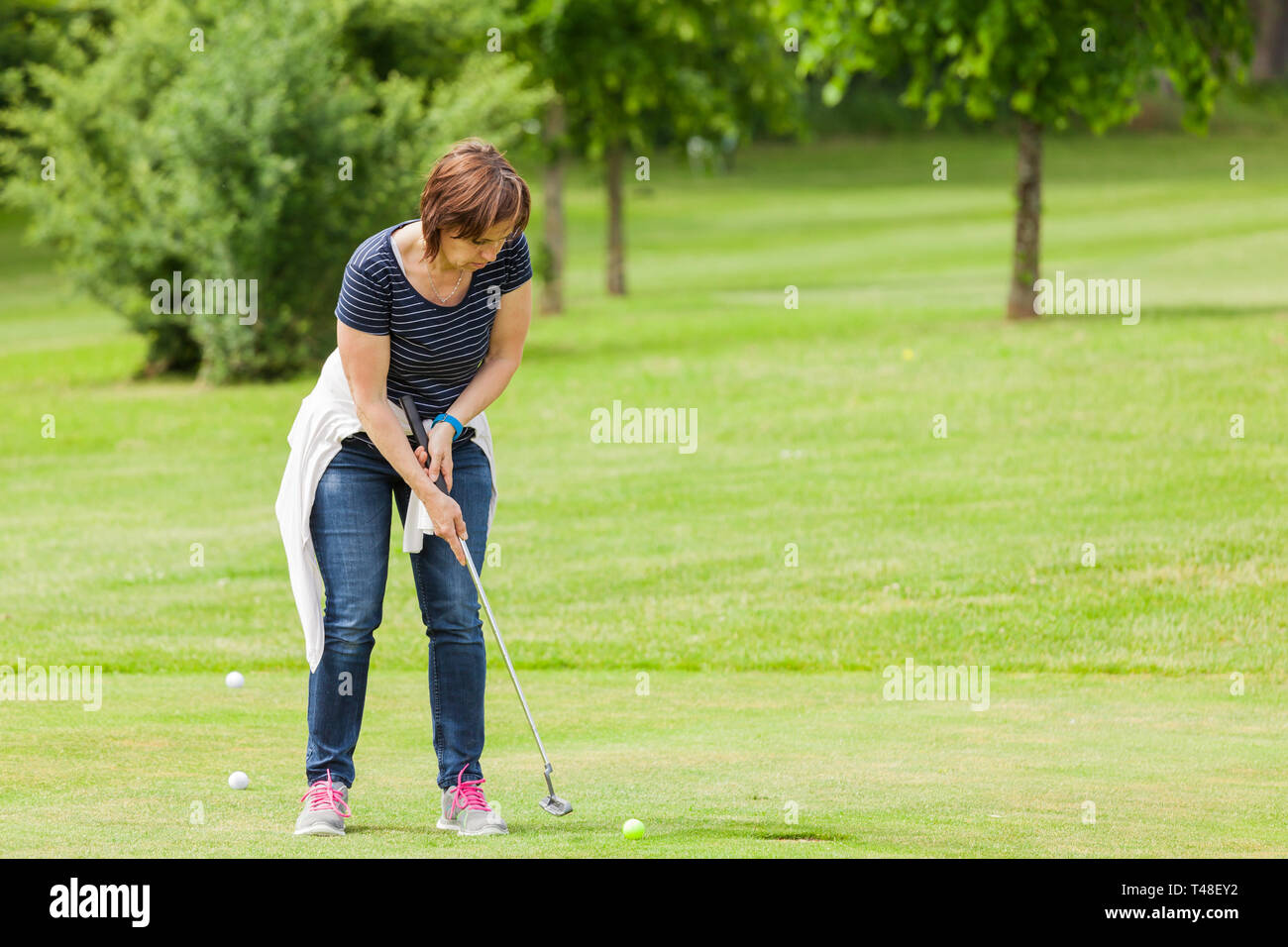 La donna a mettere sul campo da golf Foto Stock