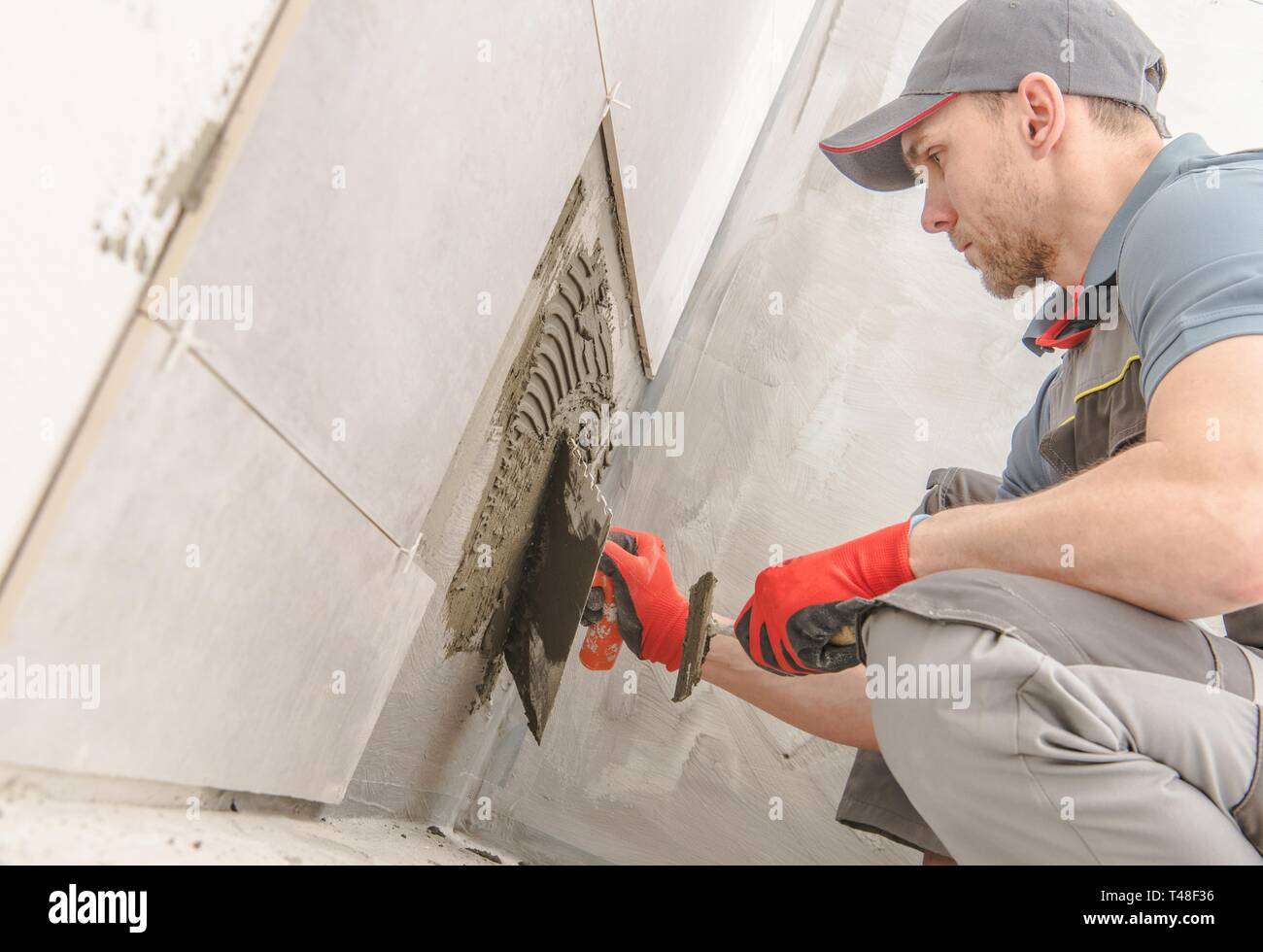 Bagno Piastrelle Ceramiche Installer. Costruzione caucasica lavoratore nel suo 30s. Foto Stock