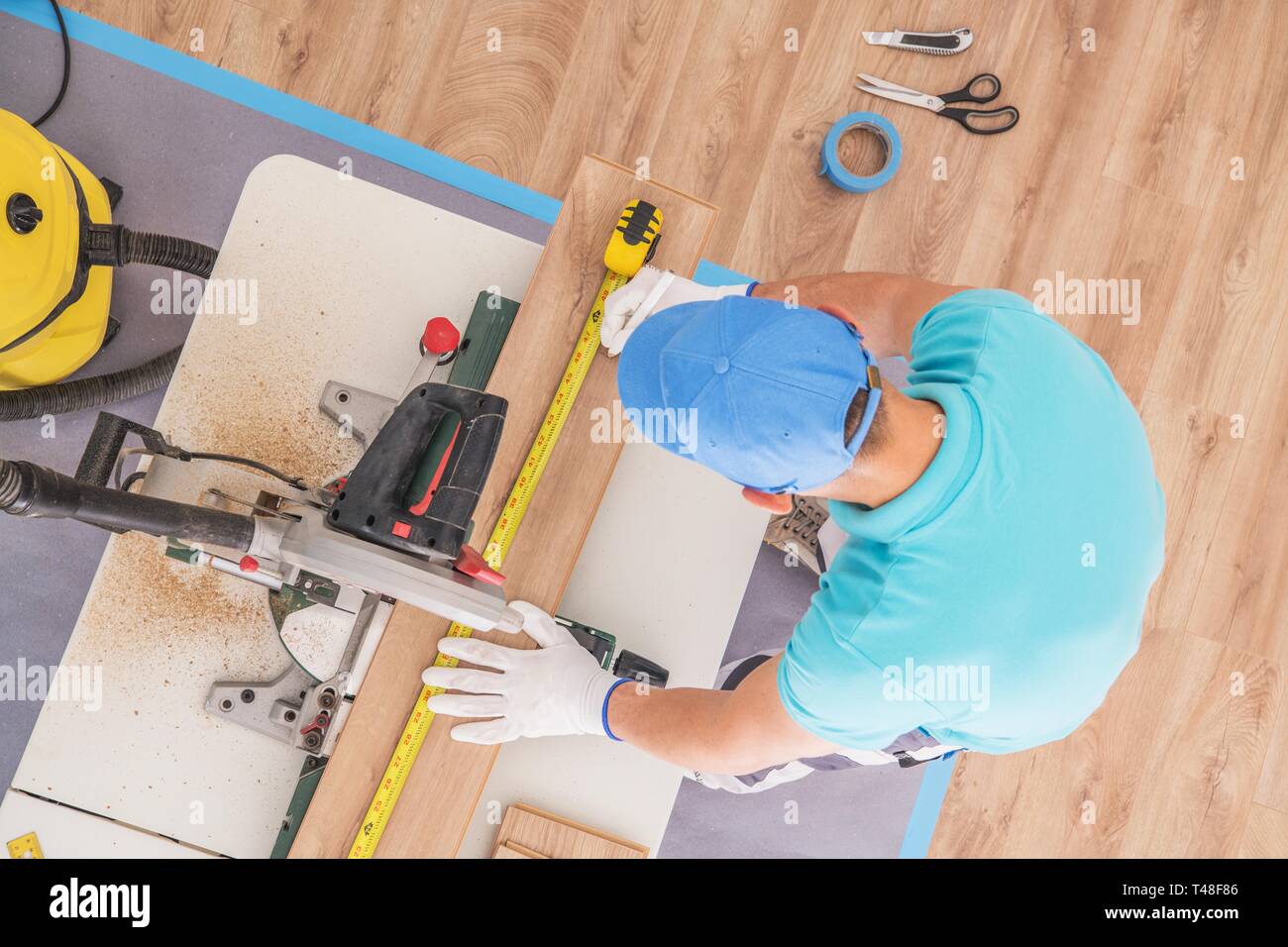 Pavimentazione contraente al lavoro. Rimodellamento caucasica lavoratore pezzo di taglio del pannello laminato utilizzando Tavola circolare Sega. Il legno come pannelli di pavimento. Foto Stock