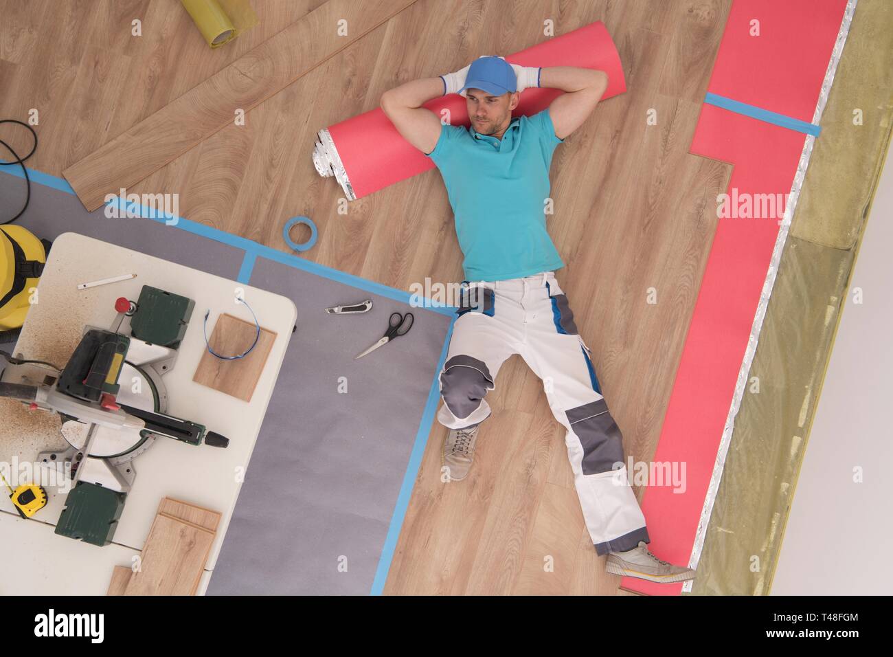 Successo di uno specialista di pavimentazione tenendo una breve vacanza per godere di nuovi posti di pannelli di legno. Tema di costruzione. Foto Stock