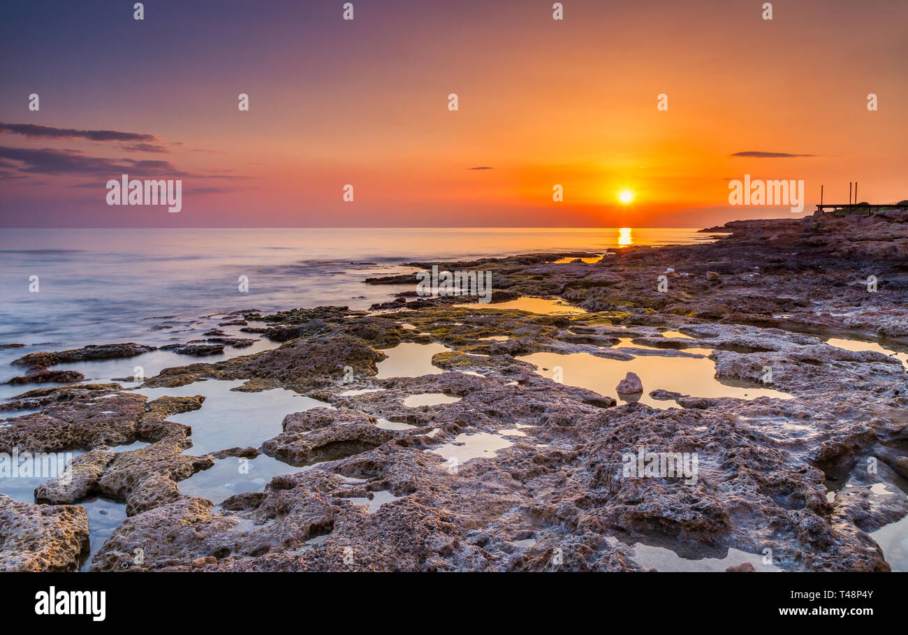 Tramonto lungo la splendida costa rocciosa vicino a Paphos sulla costa occidentale dell'isola di cipro. Foto Stock