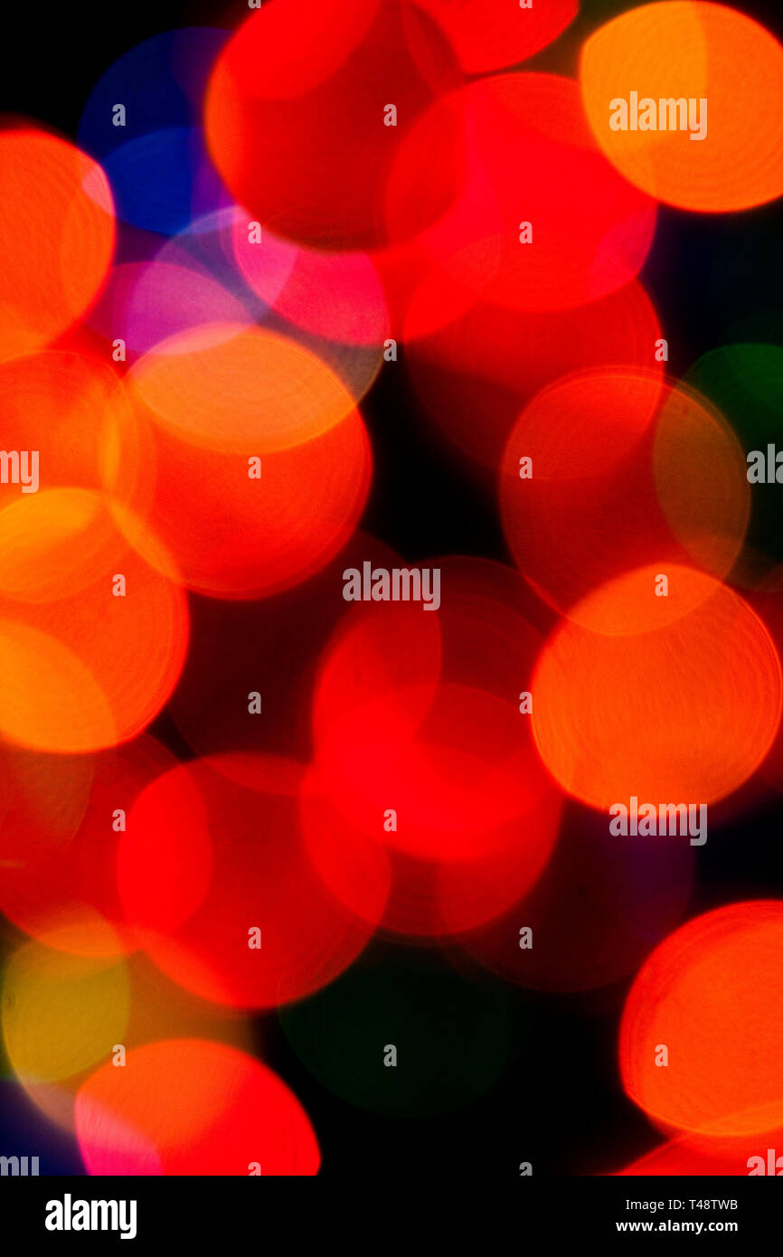 Le luci delle fate dell'albero di Natale, leggermente sfocate, illuminano rossi, verdi e oro vivaci, creando un caldo e festoso sfondo bokeh di magia natalizia. Foto Stock