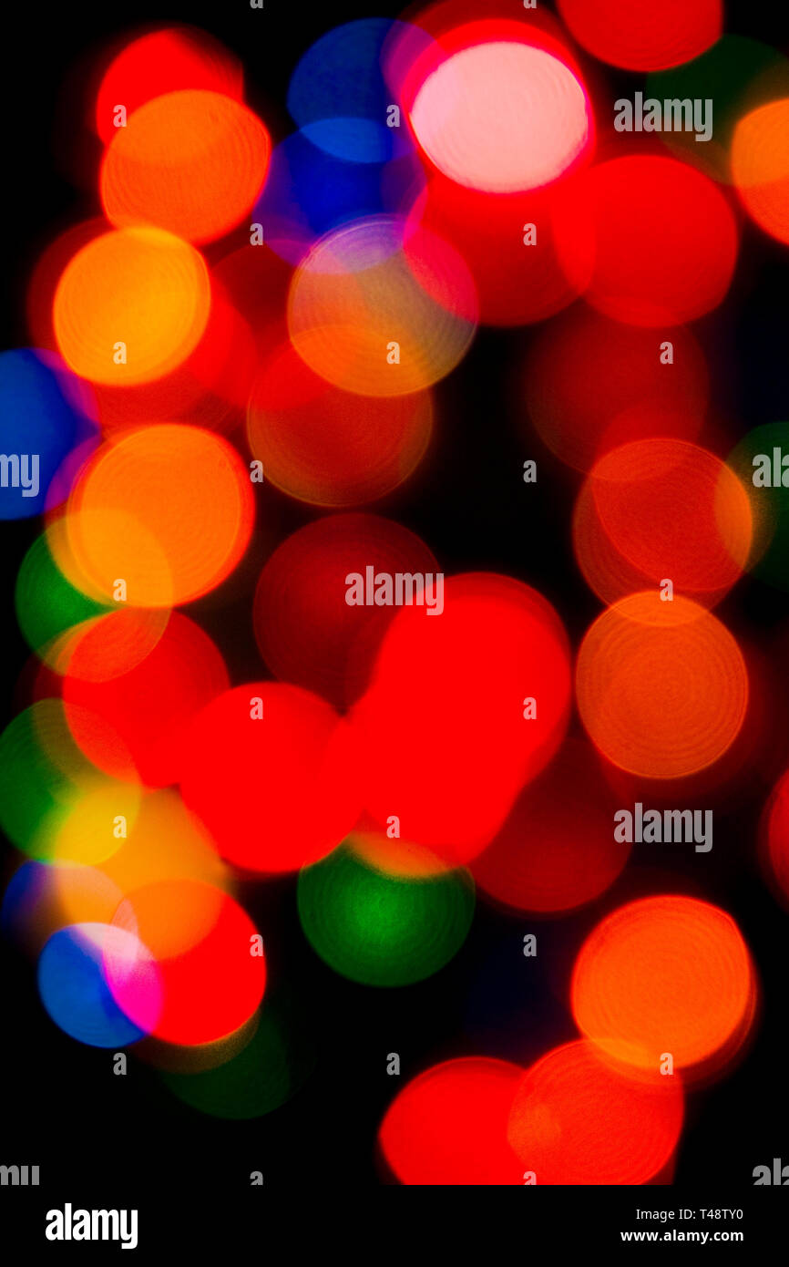 Le luci delle fate dell'albero di Natale, leggermente sfocate, illuminano rossi, verdi e oro vivaci, creando un caldo e festoso sfondo bokeh di magia natalizia. Foto Stock