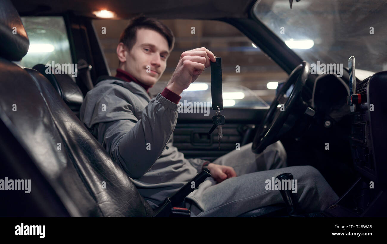 Fotografia del lato del guidatore maschio tenendo premuto i tasti seduti in auto. Foto Stock