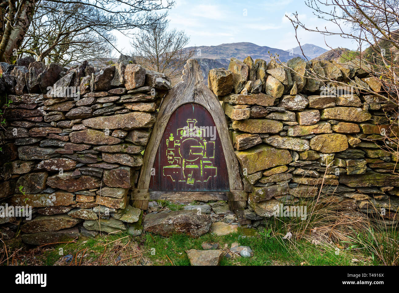 Taglio metallo immagine vintage di locomotiva a vapore in cornice di legno impostato nel muro di pietra sul sentiero in Beddgelert, Galles il 9 aprile 2019 Foto Stock