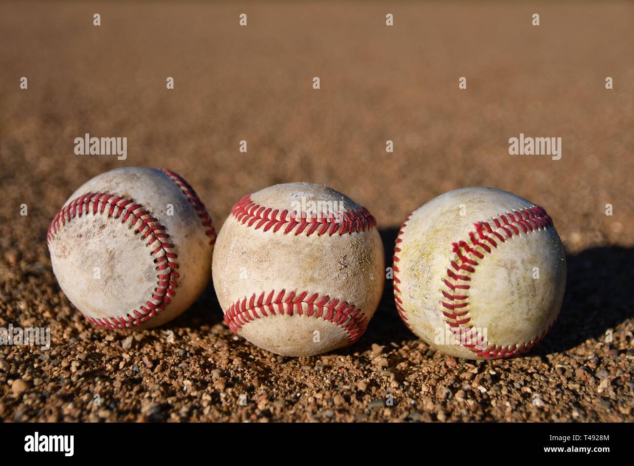 Foto di tre gioco baseballs utilizzato su un baseball infield in una giornata di sole Foto Stock