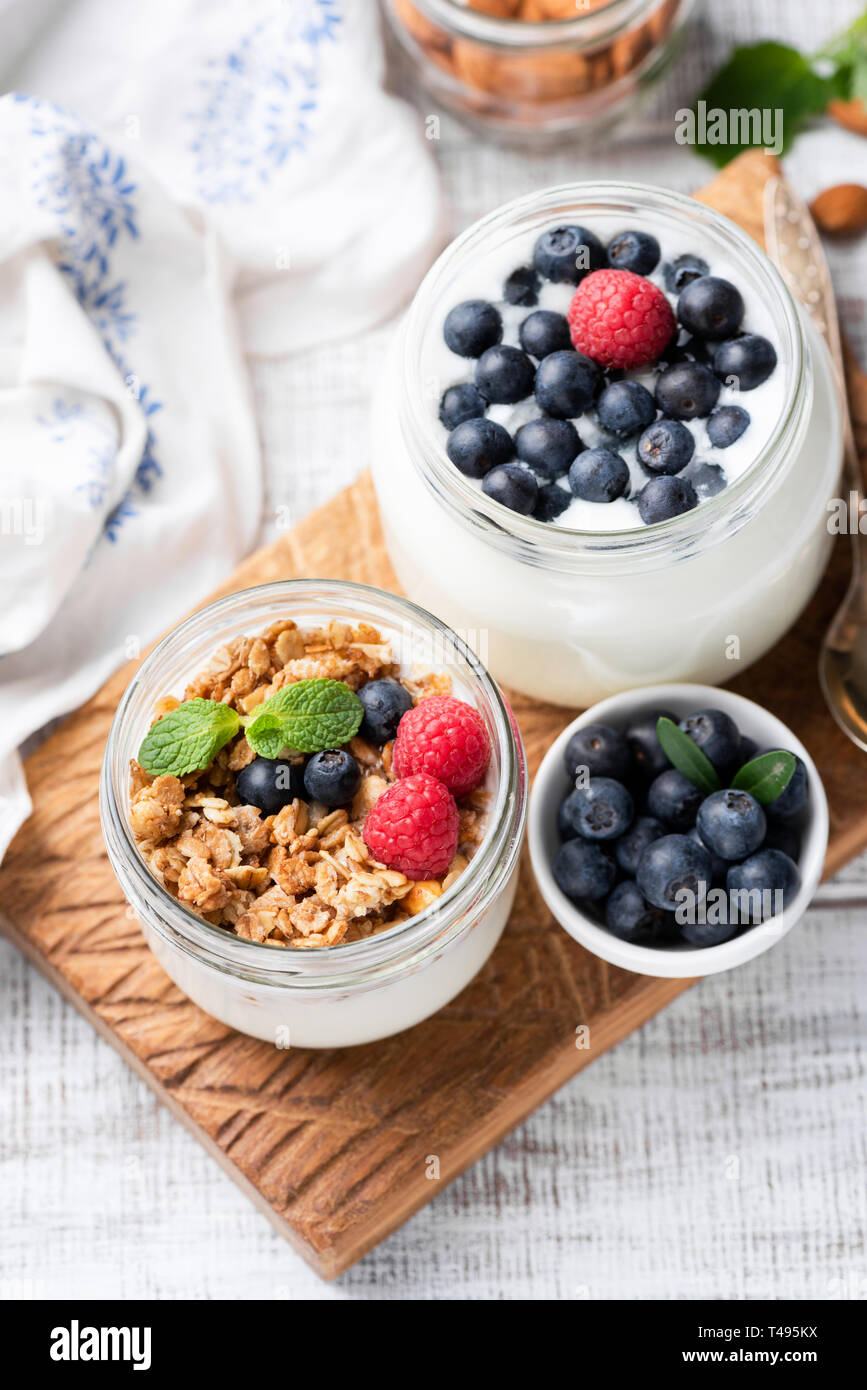 Muesli, mirtilli e lamponi e yogurt nel barattolo sulla tavola di legno. Vista superiore Foto Stock