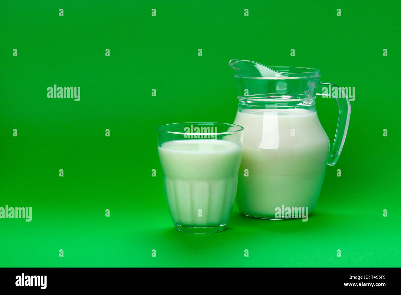 Il vaso e bicchiere di latte isolate su sfondo verde con copia spazio per testo, prodotti lattiero-caseari Nozione Foto Stock