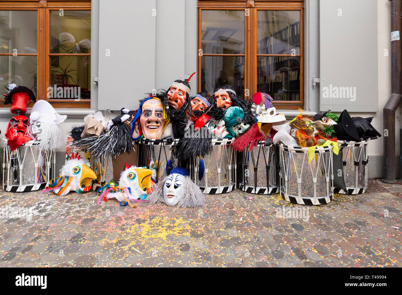 Augustinergasse, Basilea, Svizzera - Marzo 12th, 2019. Maschere di Carnevale e rullanti impilati in un angolo di strada Foto Stock