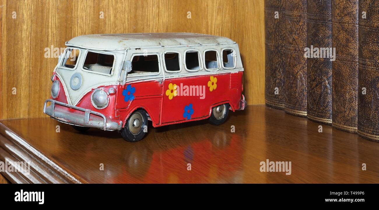 Vecchi giocattoli di latta, qui un bus rosso o VW vettura dipinta con fiori Foto Stock