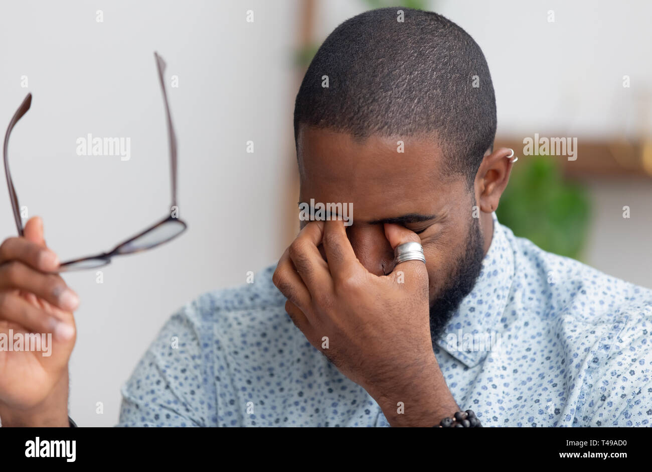 Stanco imprenditore africano di decollare bicchieri sfregamento asciutto occhi irritati Foto Stock