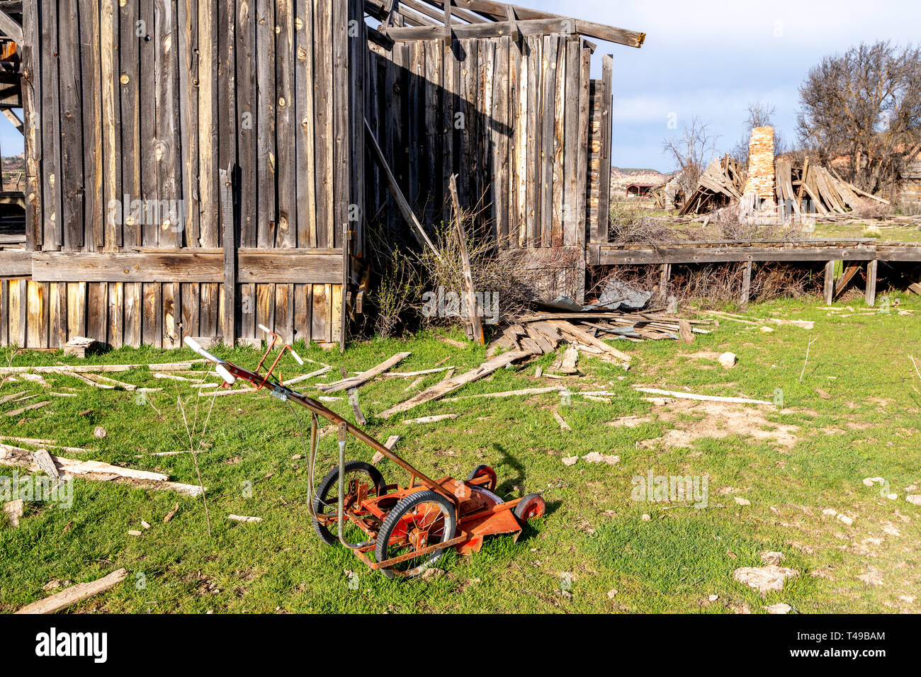 Strano cercando di antiquariato tosaerba metallici nei pressi di un fatiscente edificio occidentale Foto Stock
