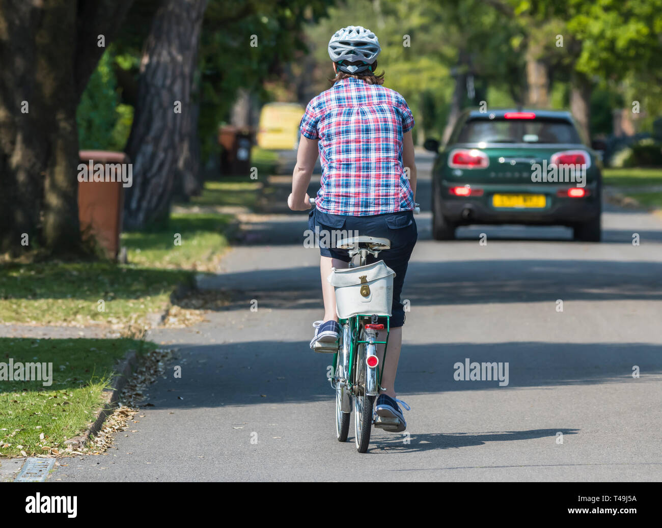Vista posteriore da dietro di un auto passando un ciclista come essi corsa di distanza su di una tranquilla strada privata nel Regno Unito. Foto Stock