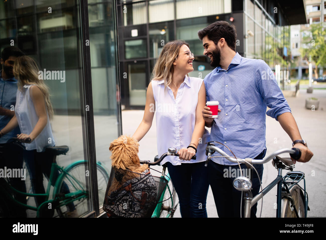 Sorridente coppia giovane di andare per un giro in bici in una giornata di sole in città Foto Stock