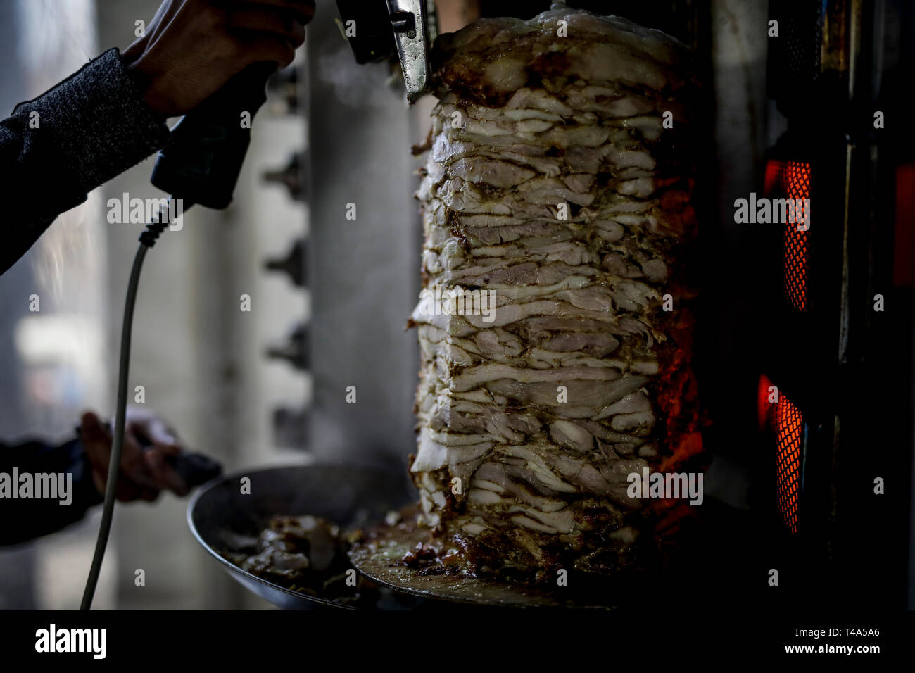 Shwarma fresca fatta sul grill e grill l uomo è il taglio del Shwarma per servire. Foto Stock