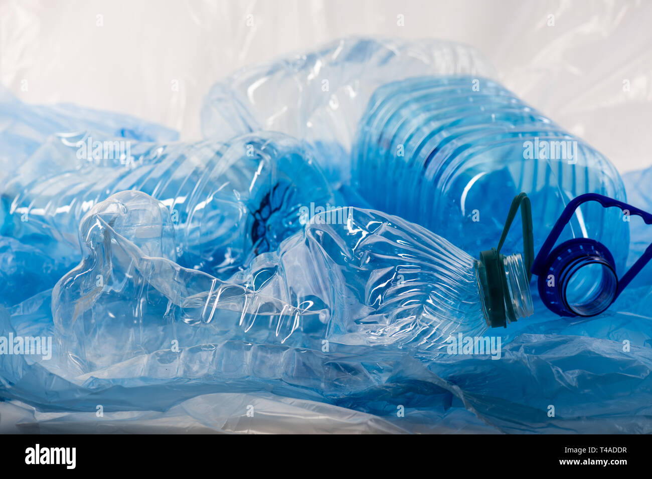 Pila di blu chiaro le bottiglie e i sacchetti di plastica gettati insieme Foto Stock