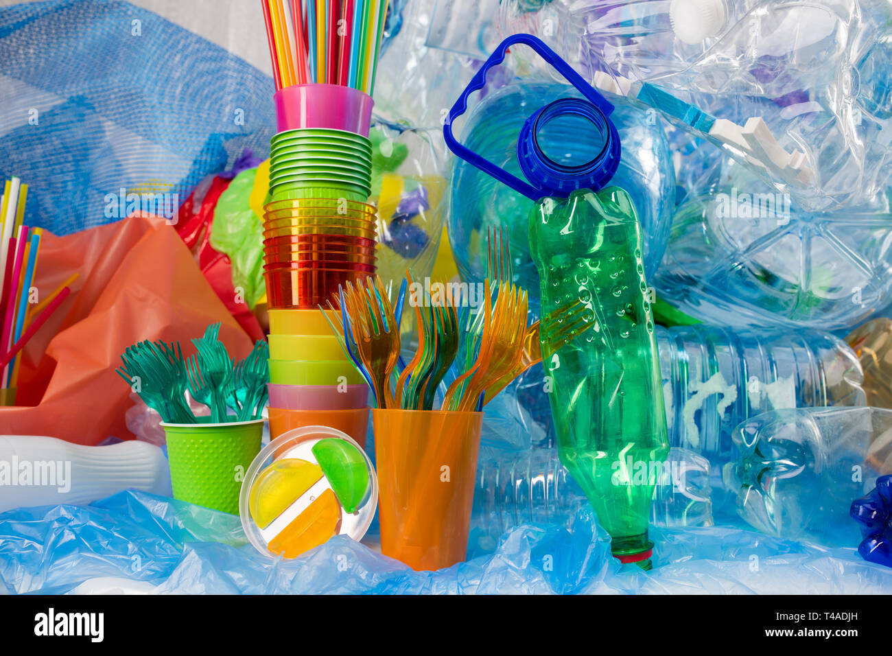 Pila di posate di plastica posto tra bottiglie usate e cannucce colorate Foto Stock