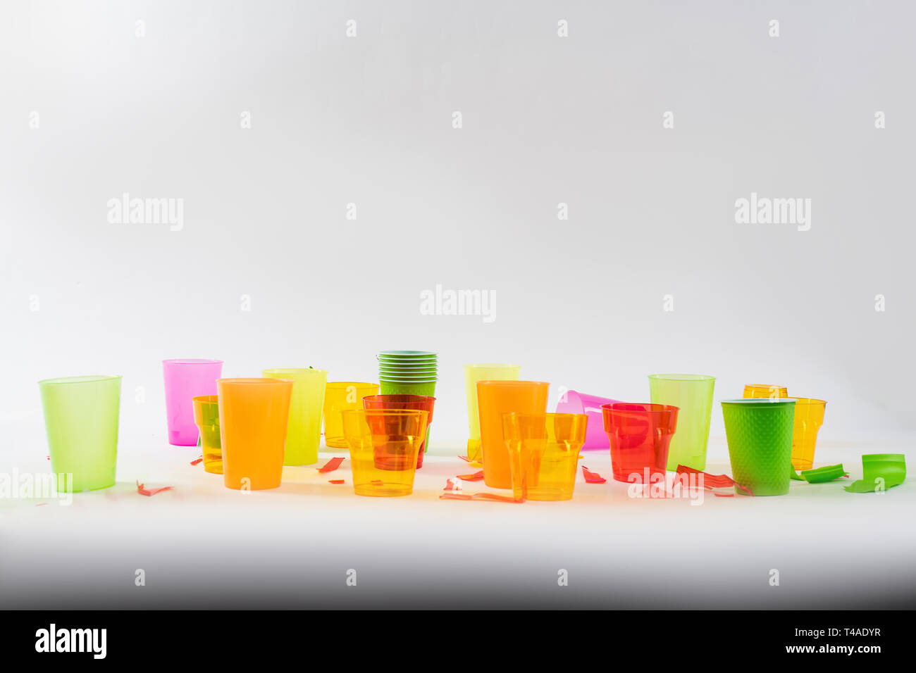 Luminose colorate con bicchieri di plastica in piedi con pezzi rotti intorno Foto Stock