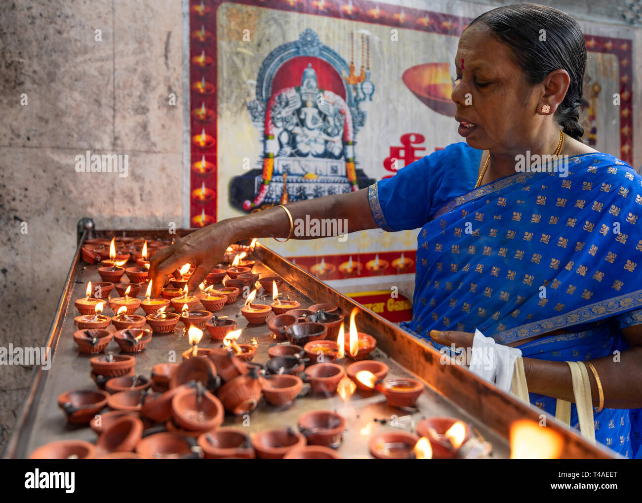 Posizione orizzontale Ritratto di signora di illuminazione un olio lampada a un tempio in India. Foto Stock