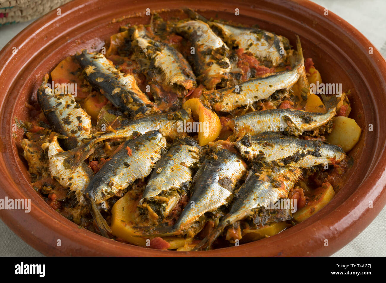 Tradizionale Tagine marocchino con le sardine e le verdure sul tavolo per la cena Foto Stock