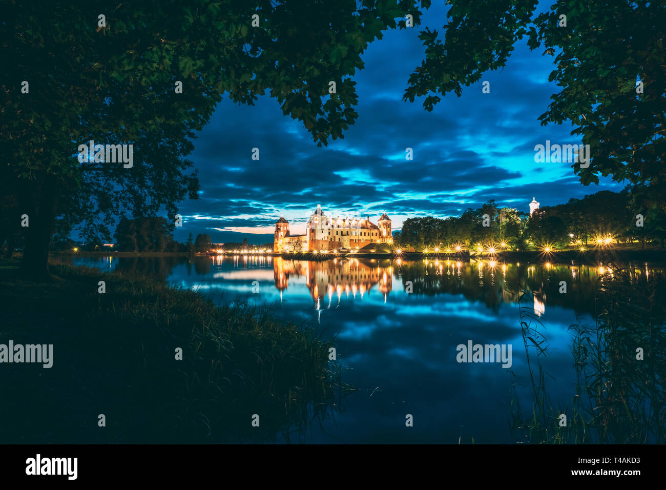 Mir, Bielorussia. Notte Vista panoramica del Castello di Mir In illuminazione serale con candelette di riflessioni sul lago di acqua. UNESCO - Sito Patrimonio dell'umanità. Famoso punto di riferimento Foto Stock