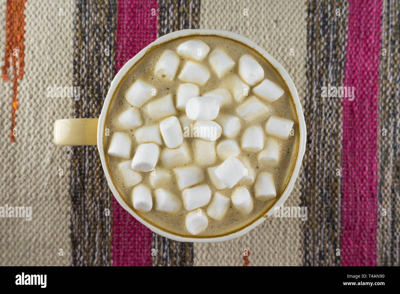 Bella tazza di caffè con marshmallow. Tessuto a righe dello sfondo. Lay piatto. Foto Stock