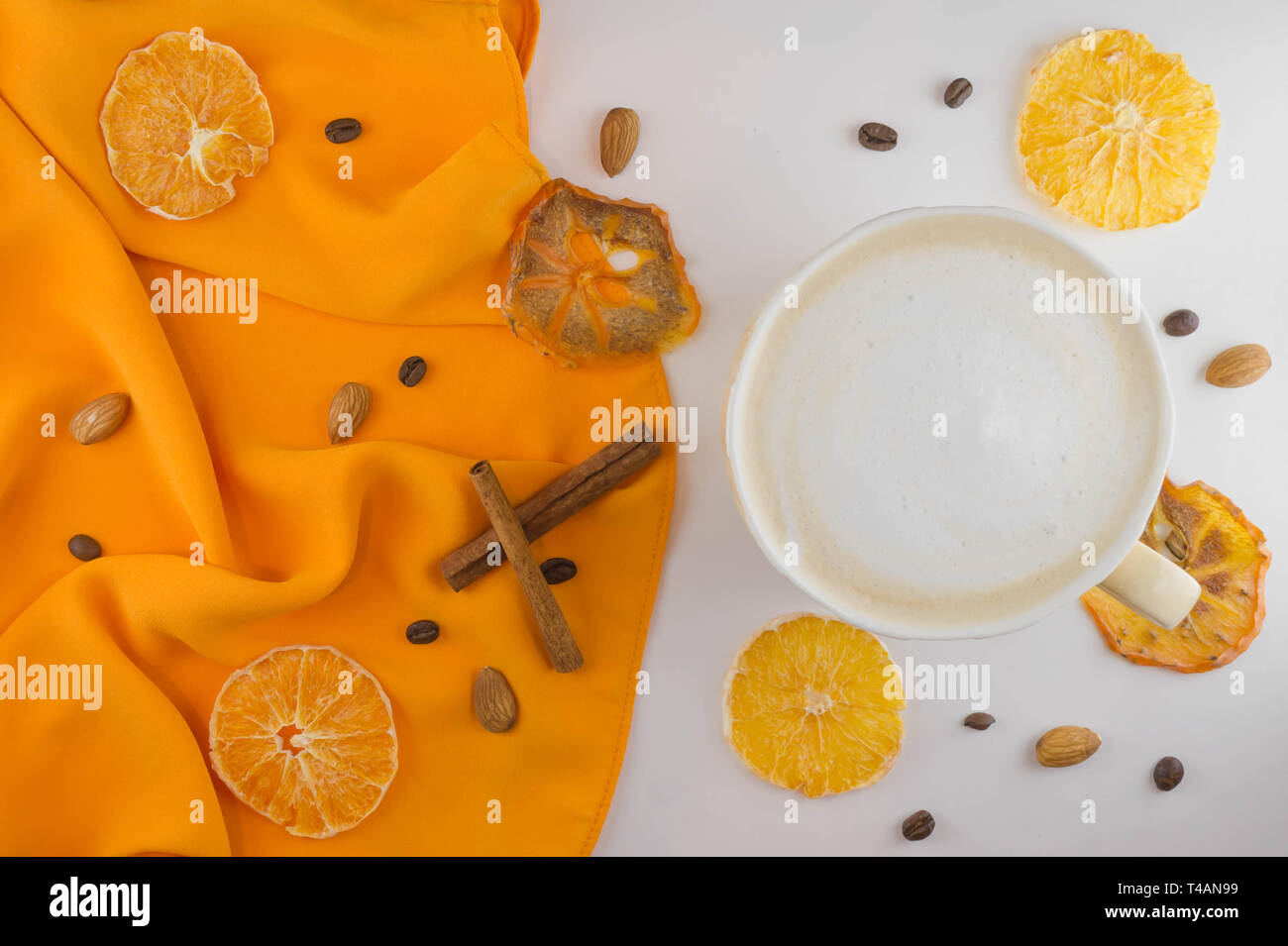Una tazza di caffè in un accogliente stile su uno sfondo bianco e di un tessuto di colore arancione. Fette di arancia essiccata e kaki. Lay piatto. Foto Stock