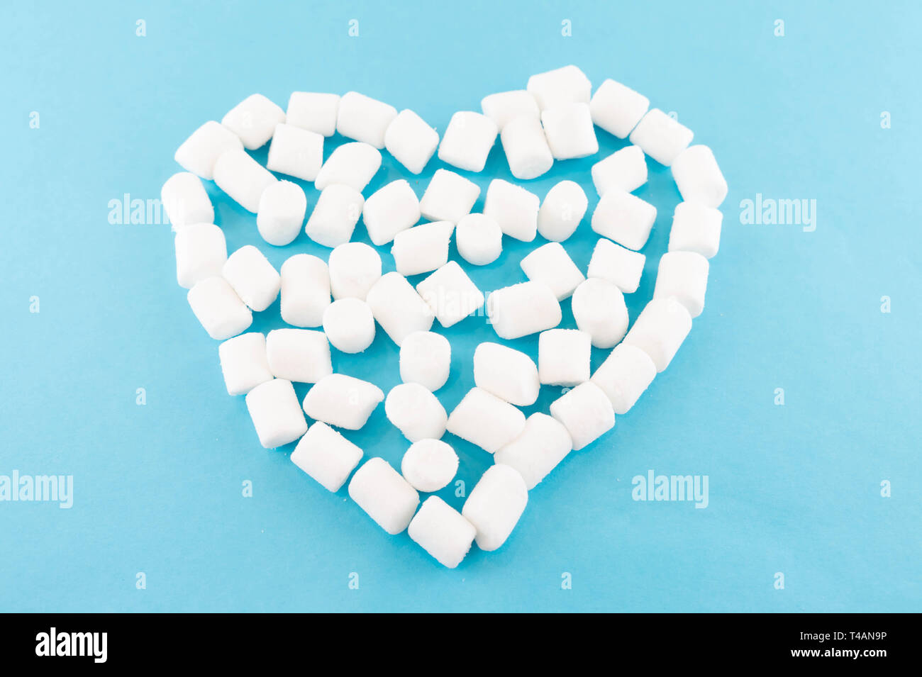 Carta blu sfondo con un cuore di marshmallow. Accogliente dolce sfondo. Foto Stock