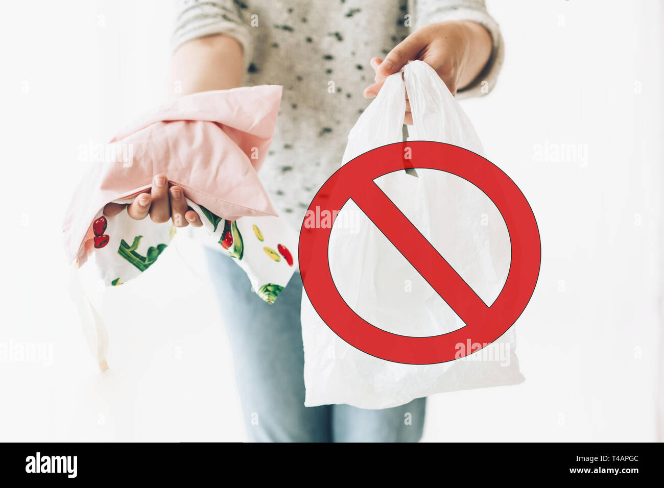 Divieto di uso singolo in plastica, segno di stop. Rifiuti Zero il concetto di shopping. Donna che mantiene in una mano i generi alimentari in riutilizzabili sacchetto eco e in altre verdure in pla Foto Stock