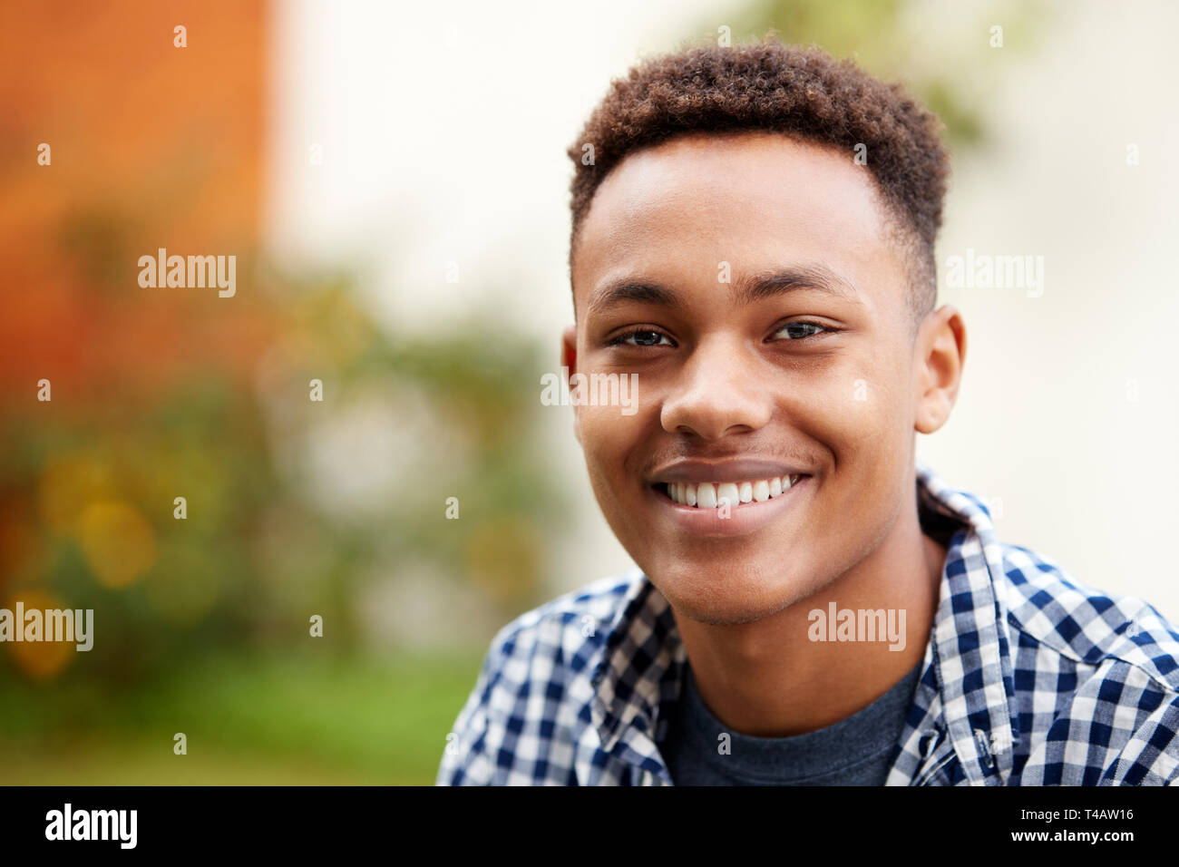 Giovane uomo nero all'aperto a sorridere alla telecamera, vicino, testa e spalle Foto Stock